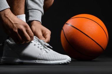 Siyah arka planda ayakkabı bağı bağlayan erkek basketbolcu, yakın plan.