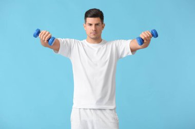 Renkli arka planda dambılları olan sportif genç adam eğitimi.