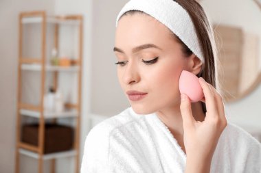 Süngerli güzel bir kadın evde makyaj yapıyor.