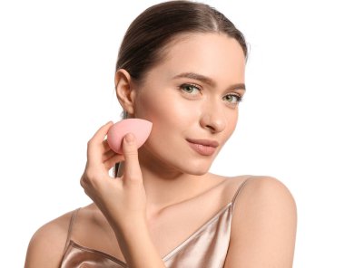 Beyaz arka planda makyaj süngeri olan güzel bir genç kadın.