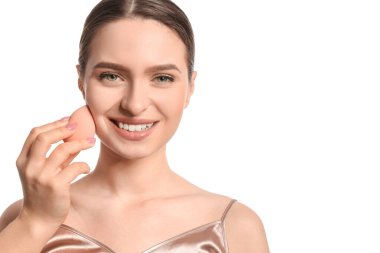 Beyaz arka planda makyaj süngeri olan güzel bir genç kadın.