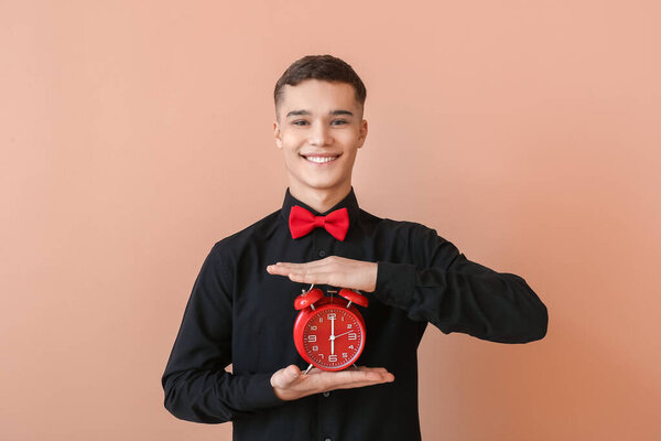 Teenager with alarm clock on color background