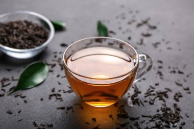 Bir fincan sıcak çay ve koyu arkaplanda kuru yapraklar.