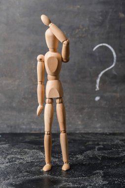 Koyu arkaplanda soru işareti olan tahta manken.