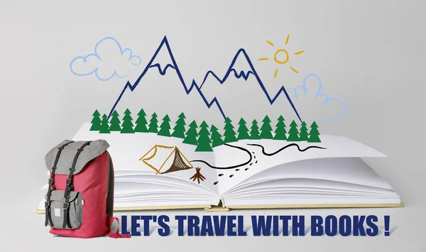 Open book with traveler's backpack and drawn mountain resort on grey background