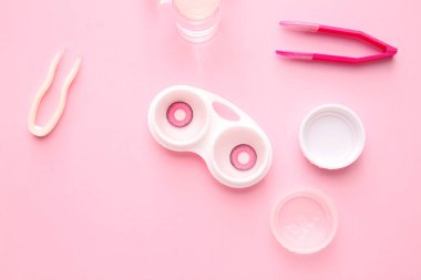 Solüsyon şişesi, cımbız ve kontak lensli konteynır renk arkaplanı