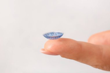 Açık arkaplanda kontakt lensli kadın parmak