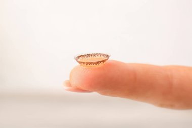 Açık arkaplanda kontakt lensli kadın parmak