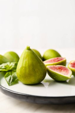 Açık arkaplanda taze yeşil incir tabağı, yakın plan.