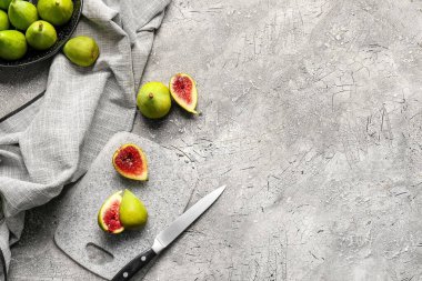 Taze yeşil incirli tahta ve gri arka planda bıçak.