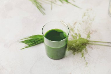 Açık arkaplanda taze buğday çimi suyu.