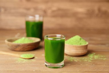 Taze buğday çimi suyu ve ahşap zemin üzerinde pudra.