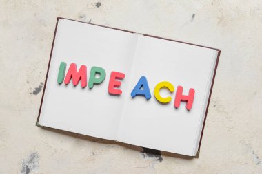 Işık arkaplanı üzerine kitap ve kelime IMPEACH