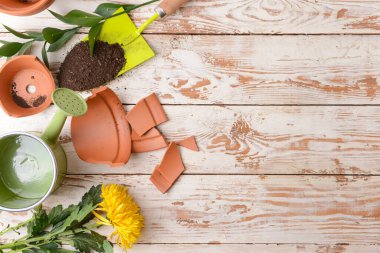 Kırık saksı ve ahşap masada bahçe aletleri.