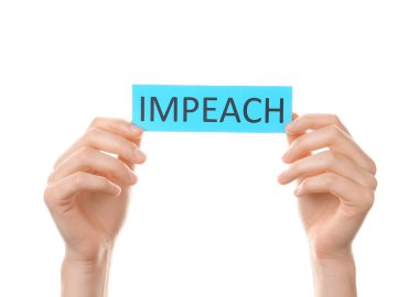 Beyaz arkaplanda IMPEACH yazılı kağıt tutan eller