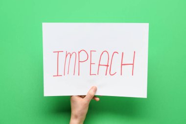 Renk arkaplanı üzerinde IMPEACH metin içeren el ele tutuşan kağıt