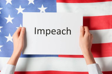 ABD bayrağına karşı IMPEACH yazılı kağıt tutan eller