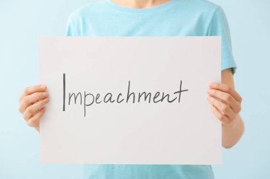 Renk arkaplanı üzerinde IMPEACHMENT yazan kağıt tutan kadın