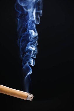 Esmer arka planda dumanlı sigara.