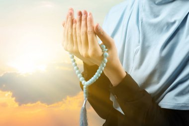 Tespih taşıyan Müslüman kadın gün batımında dua ediyor