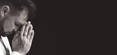 Dindar bir adamın siyah beyaz portresi Tanrı 'ya karanlık arka planda dua ediyor.