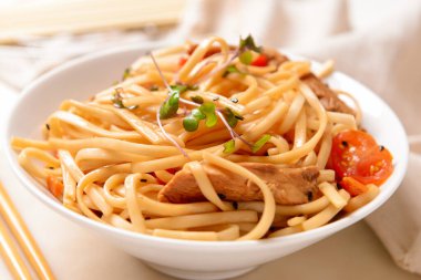 Plate with tasty noodles and meat on light background, closeup