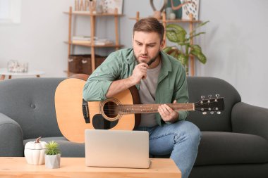 Genç adam evde online müzik dersleri alıyor.