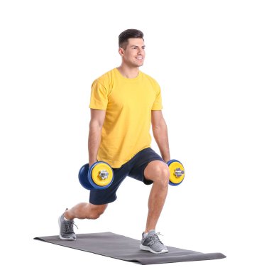 Beyaz arka planda dambılları olan sportif genç adam eğitimi.