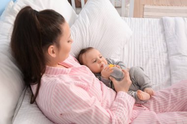 Evinde bir şişe su ve tatlı bir erkek çocuğu olan genç bir anne.