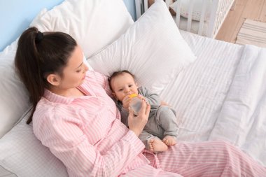 Evinde bir şişe su ve tatlı bir erkek çocuğu olan genç bir anne.