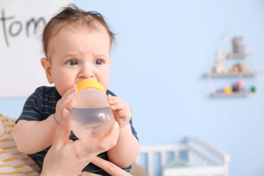 Evdeki biberondan su içen tatlı bir oğlan.