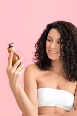 Renkli arka planda kozmetik ürünleri olan güzel genç bir kadın.