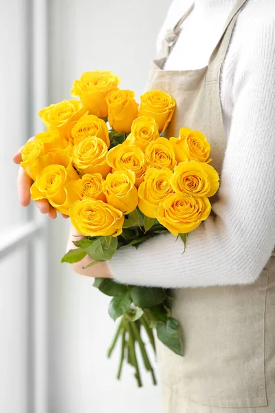 Female florist with beautiful yellow roses in room