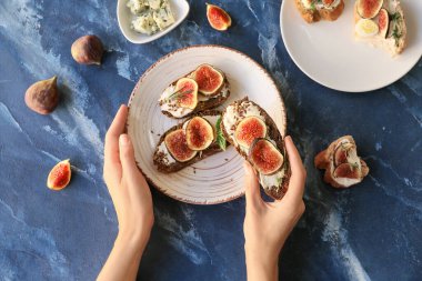 Renkli incirli lezzetli sandviç tutan bir kadın.