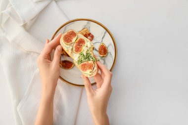 Beyaz arka planda incirli lezzetli sandviç tutan bir kadın.