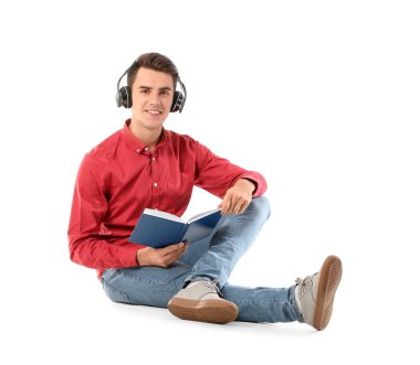Kulaklıklı genç adam beyaz arka plan üzerine kitap okuyor.