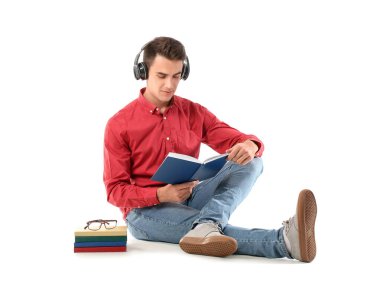 Kulaklıklı genç adam beyaz arka plan kitapları okuyor.