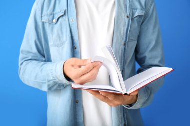 Renkli arka plan kitabı olan genç adam, yakın plan.