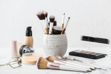 Hafif arkaplanda makyaj fırçaları ve dekoratif kozmetik setleri