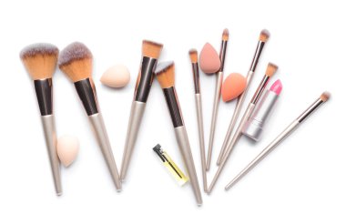 Beyaz arka planda makyaj fırçaları, süngerler ve dekoratif kozmetikler.