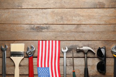 Ahşap arka planda bir takım aletler ve Amerikan bayrağı. İşçi Bayramı kutlamaları