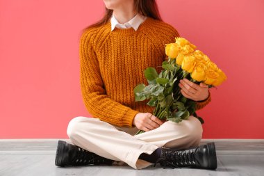 Renkli duvarın yanında güzel sarı gülleri olan genç bir kadın.