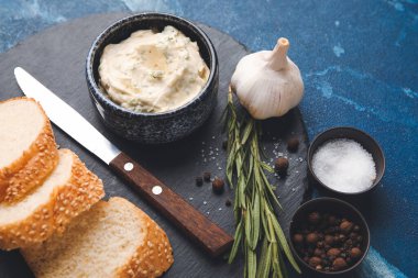 Taze ekmek dilimleri, sarımsaklı tereyağı ve arka plandaki malzemeler, yakın plan.