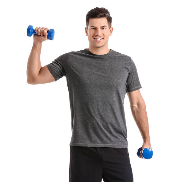Sporty young man training with dumbbells on white background
