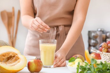 Mutfaktaki masada kavun püresi ile kadın ve cam.