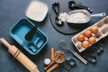 Koyu arkaplanda fırın hazırlamak için mutfak gereçleri ve malzemeler.