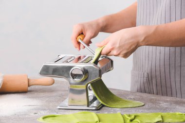 Masada hamur ve makarna makinesi olan kadın.