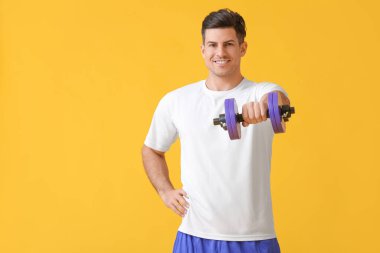 Renkli arka planda dambıl olan sportif genç adam eğitimi.