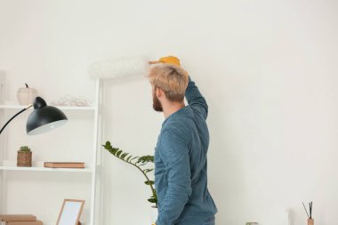 Genç adam dairesini temizliyor.