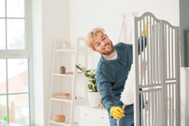 Genç adam dairesini temizliyor.